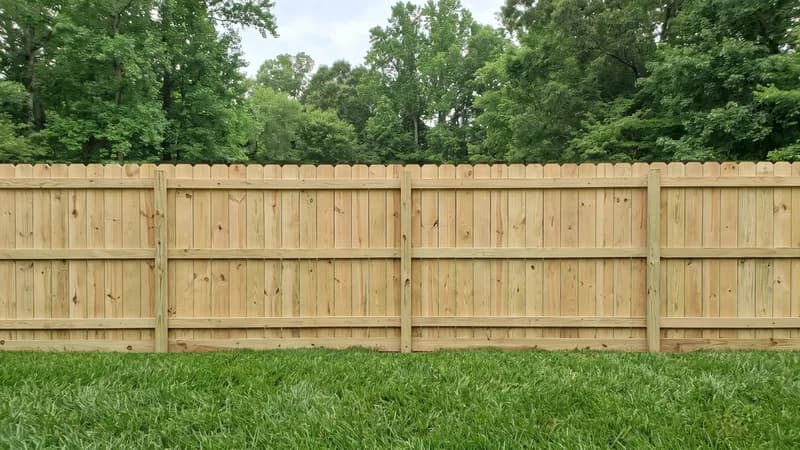 Cedar wood privacy fence with cap rail along a green suburban lawn at golden hour